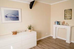 a white room with a fireplace and a white dresser at Bauernhof Marquardt in Fehmarn