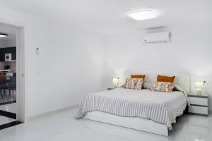a white bedroom with a bed with pillows at Brisa 3 in La Santa
