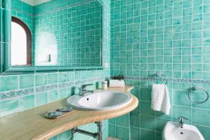 a blue tiled bathroom with a sink and a mirror at Belvedere in San Teodoro +17 photos