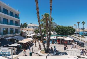 a group of people walking around a street with palm trees at Port House in Kos