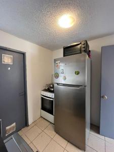 a kitchen with a stainless steel refrigerator and a stove at Casa Dichato Equipada in Tomé