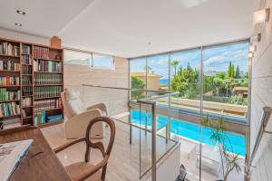a living room with a library and a swimming pool at Villa Agusmar in Llucmajor