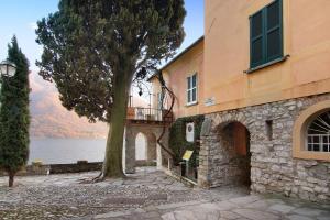 a building with a tree next to the water at Fogazzaro Lake View Apartment in Oria