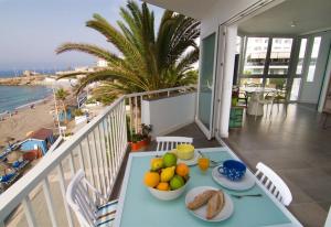 a table with plates of fruit on a balcony with the beach at Super Front Line Modern New Apartm in Nerja