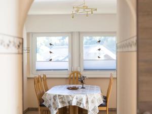 a dining room with a table and two windows at Haus Wanderglück in Schmallenberg