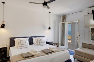 a bedroom with a large white bed and a couch at Blueros - Sand Suite in Megas Gialos - Nites +23 photos