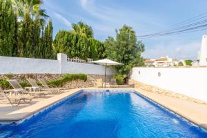 a swimming pool with chairs and an umbrella at Villa Margarita in Benissa