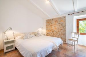 a white bedroom with a bed and a chair at Els Garroverets in Binissalem +17 photos