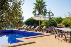 a pool with chairs and a table and an umbrella at Ses Angoixes in Santanyi