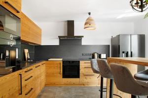 a kitchen with wooden cabinets and a black stove at Chalet Sonnenwald in Grattersdorf