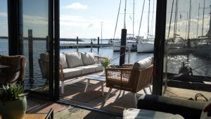 a porch with a couch and chairs on a boat at Hausboot mit Motorboot in Heiligenhafen