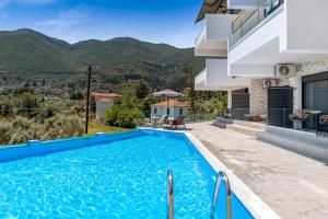 a villa with a swimming pool and mountains in the background at Oceanida Afrodite Lyxury Suite in Nikiana