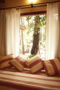 ventana con cortinas blancas y almohadas en una cama en Rincón de los Vientos en Mar de las Pampas