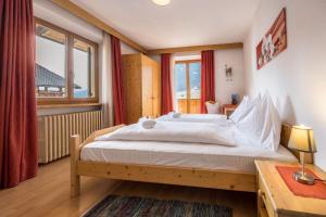 a bedroom with a large bed and a desk and window at Manuel's App Watschinger -Edelweiss in Sesto