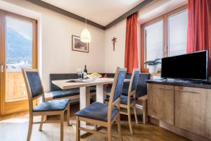a dining room with a table and chairs and a television at Manuel's App Watschinger -Edelweiss in Sesto