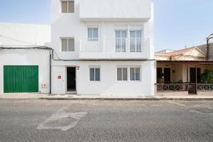 a white house with a green door on a street at Campo Amor Alto in Arrecife