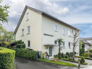 a large white house with bushes and trees at Straub in Meckenbeuren