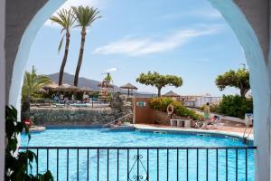 a pool at a resort with palm trees and people swimming at Dalias Nerja in Nerja