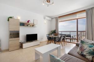 a living room with a couch and a television and a table at Primera linea vistas panoramicas in Torremolinos