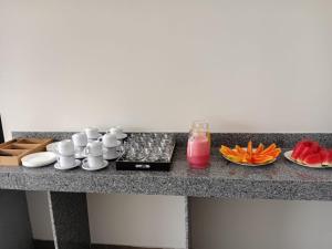 a table with food and a drink and plates of fruit at Hotel AG3 in Teixeira de Freitas