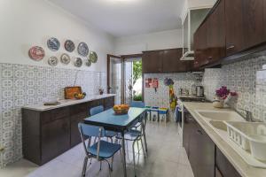 a kitchen with wooden cabinets and a blue table and chairs at Casa Tangerina in Tavira