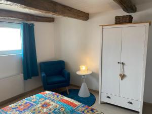 a bedroom with a bed and a blue chair at La petite Cocotte in Marcheseuil