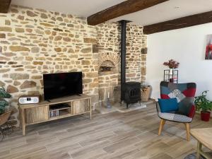 a living room with a tv and a stone wall at La petite Cocotte in Marcheseuil