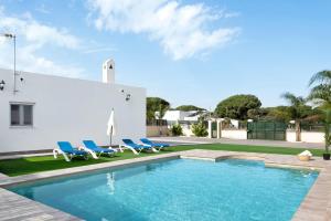 a swimming pool with blue chairs and a building at Villa Montenmedio - Juande in El Soto
