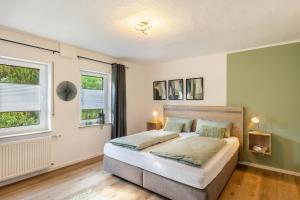 a bedroom with a large bed and two windows at Ferienwohnung-Bachlauf-Eslohe in Eslohe