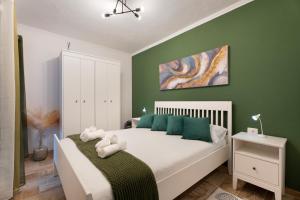 a bedroom with a white bed with green walls at Los Almendr2s in Frontera