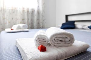 a pile of towels on a bed with a red rose at La Villa in Mantova +22 photos