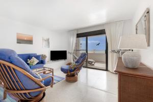 a living room with blue chairs and a television at Beach House Christine in Costa Calma