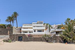a large white house on the beach with palm trees at Beach House Christine in Costa Calma