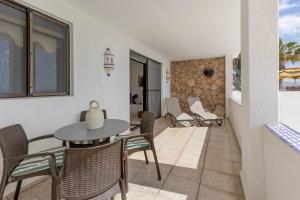 a dining room with a table and chairs and a stone wall at Beach House Christine in Costa Calma