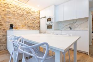a white kitchen with a white table and chairs at Casa del Campanar in Traiguera