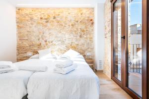 a bedroom with two beds and a stone wall at Casa del Campanar in Traiguera