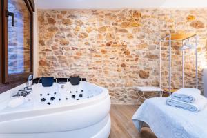 a bathroom with a white tub and a stone wall at Casa del Campanar in Traiguera +22 photos
