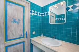 a blue tiled bathroom with a sink and a mirror at Pavoncella in Orosei +22 photos