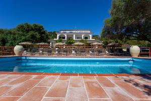 a swimming pool with chairs and a building in the background at Pavoncella in Orosei