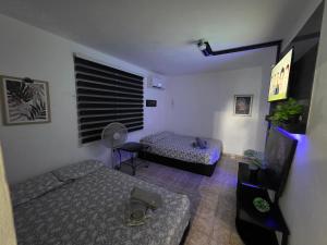 a small room with two beds and a fan at Relax en el pueblo 2 in Fajardo