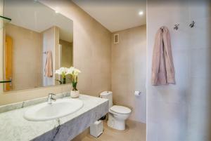 a bathroom with a sink and a toilet and a mirror at Es Port penthouse in Santanyi +16 photos