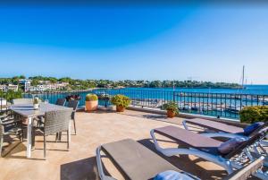a patio with a table and chairs and the ocean at Es Port penthouse in Santanyi