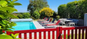 a row of chairs and tables next to a pool at Le clos du Verdelet vue mer piscine in Planguenoual