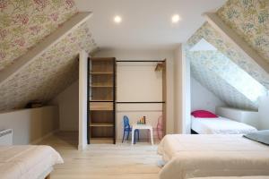 a attic bedroom with two beds and a table at Le clos du Verdelet vue mer piscine in Planguenoual