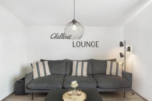 a living room with a gray couch and a chandelier at Ferienwohnung Jule in Arnsberg
