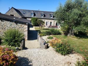 a house with a stone wall and a garden at Le clos du Verdelet vue mer piscine in Planguenoual