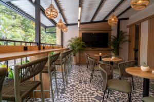 a bar with tables and chairs and a flat screen tv at Bruma Verde Casa Hotel in Medellín