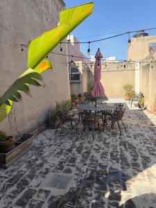 an outdoor patio with a table and an umbrella at Spacious house just steps from the cathedral in Morelia