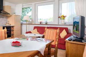 a living room with a table and a red couch at Ferienwohnung Meierhof, 38qm in Sankt Märgen