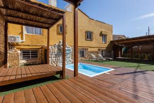 a wooden deck with a pool and a house at Masia Alt in Olerdola